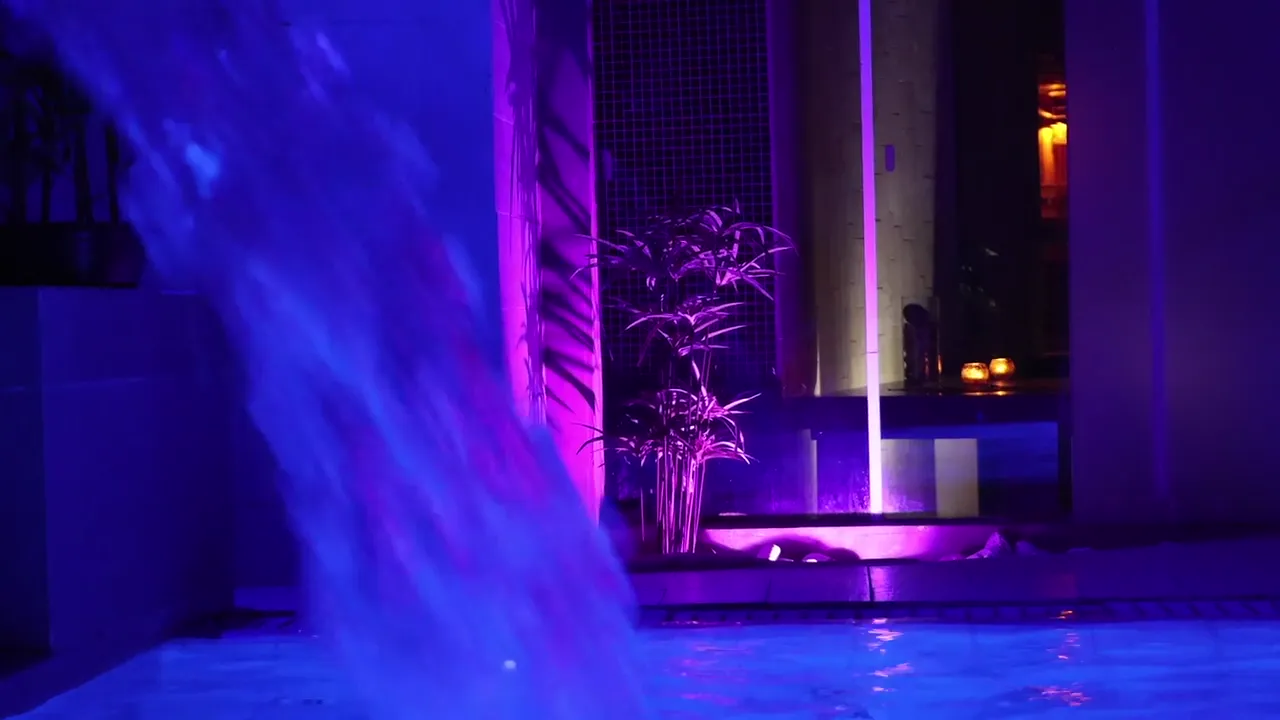 La cascata della vasca idromassaggio della SPA illuminata di luce viola